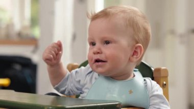 Küçük şirin bir bebek bir parça yiyecek tutuyor, gülümseyen bir bebek. Bu video yemek ve bebekle ilgili konular için mükemmel, neşe ve masumiyet yayıyor.