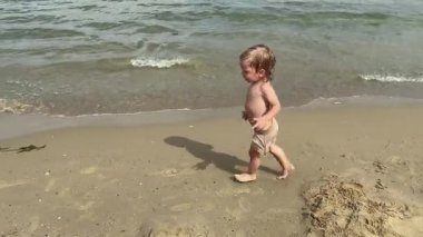Güzel sıcak bir günde, kaygısız çocuk sevinçle sahilde koşar, nazik dalgaların yanında mutlu bir şekilde oynar, çocukluğun saf masumiyetini büyüleyici güzellikler arasında yakalar.