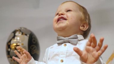 Neşeli bir çocuk, pasta kaplı elleri ve yüzüyle, doğum günlerini kutluyor, çocukluk mutluluğunun ve masumiyetin saf özünü somutlaştırıyor bu anları unutulmaz kılıyor.