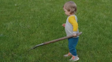 Bahçede, neşeli çocuk mutlu bir şekilde çevreyi keşfeder, bahçıvanlık aletlerini öğrenir ve bahçe işlerinin mucizelerini keşfeder.