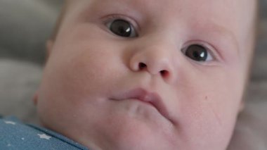 Bebek bebek, küçük ayaklarıyla neşeyle meşgul olurken rahat, yumuşak bir battaniyenin üzerinde uzanıyor, kameraya bakıyor, oyuncu masumiyetlerini, gerçek meraklarını ve kaygısız tavırlarını sergiliyor.