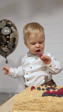 Dağınık elli ve yüzlü bebek ilk doğum günlerini büyük pasta, canlı ve renkli balonlar ve heyecanla kutluyor. Saf çocukluk sevinci ve masumiyeti somutlaştırıyor.