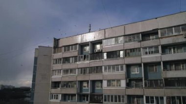 Bir apartmanın yan cephesi. Beyaz bulutlu mavi gökyüzüne karşı balkonları olan eski bir mesken binası. Düşük maliyetli çoklu konut kavramı.