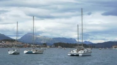 Şehrin kıyısındaki deniz koyundaki beyaz yatların panoramik görüntüsü yüksek dağların arka planına karşı. Yelkenli teknelerle seyahat etmek heyecan verici bir hobi..