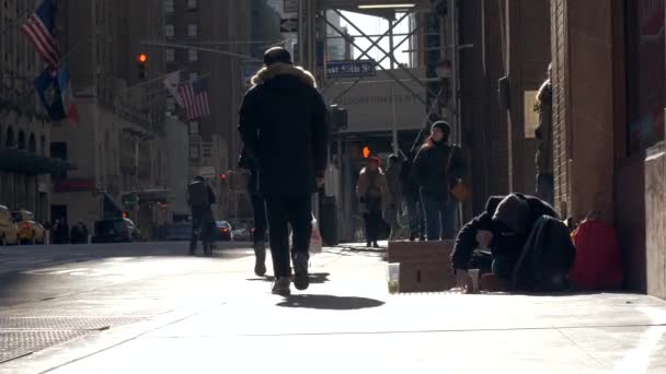 在纽约 一个无家可归的人坐在人行道上乞讨 人们若无其事地沿着人行道走过坐在人行道上的一个流浪汉 无家可归的问题概念 美国纽约 2020 — 图库视频影像
