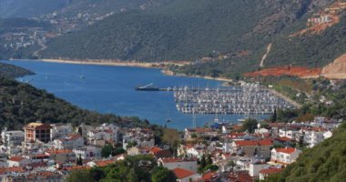 Yeşil ormanlarla kaplı dağlarla çevrili büyük bir deniz koyunun üst görüntüsü. Sahilde küçük bir tatil köyü olan büyük bir yat parkı olan Sea Bay. Küçük deniz kenarı turizm kasabaları kavramı.