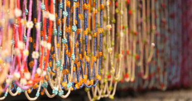 Çok renkli boncukları ve doğal malzemelerden yapılmış farklı kolyeleri olan bir gösteri. Yakın çekim ve seçici odaklanma. Doğal taşlardan ve malzemelerden yapılan halk dekorasyonu kavramı..