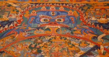 Nepal 'in resmi. Varoluşun sembolik çarkını çizmek. Kadın ellerinin bir tankı açtığı yakın plan, Nepal halkının geleneksel renkli bir tablosu olan bir parşömen..