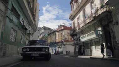 Küba 'nın başkenti Havana' nın eski dar sokakları. İki ve üç katlı dar bir cadde, park etmiş bir arabası ve yoldan geçenler var. Havanna, Küba - 01 Aralık 2022.