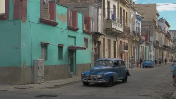 キューバの首都ハバナの貧しい地域の狭い通りに沿って古いレトロな車のドライブ レトロなアメリカ車がキューバの首都ハバナのカードを訪れています ハバナだ キューバ ハバナ 2022年12月1日 — ストック動画