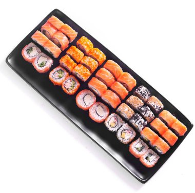 Suşi seti. Somon balıklı rulo kırmızı havyar ve siyah tabakta beyaz arka planda izole edilmiş sebzeler.