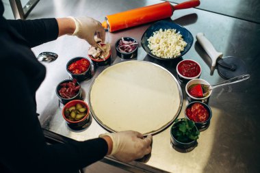 Pizza yapma süreci. İtalyan pizzası pişirmek. Mutfakta pizza yapan aşçının yakın çekimi..
