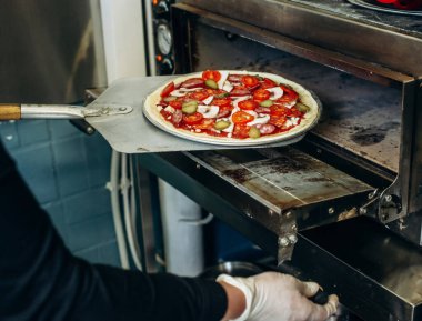 Pizzacıdaki fırına pizza koyarken yakın çekim