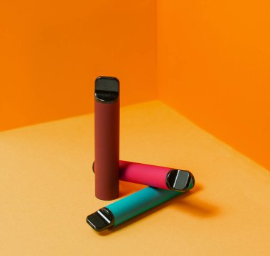 Renkli, tek kullanımlık, elektronik sigaraların rengarenk arka planda yerleşimi. Modern sigara, buhar ve nikotin konsepti.