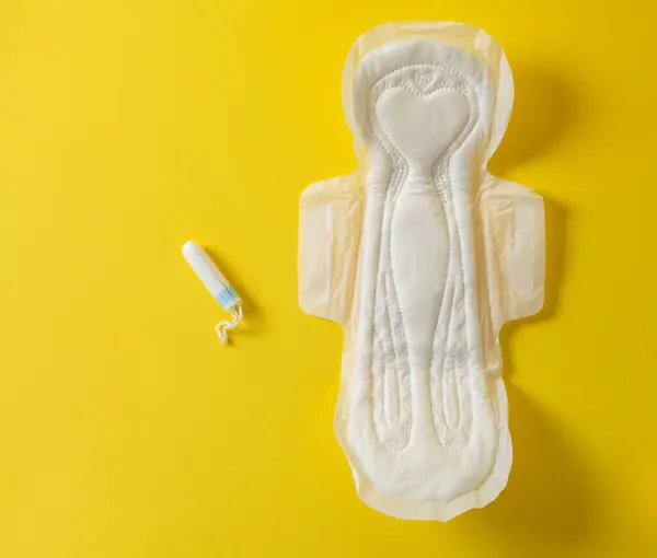 Menstrual tampon and pad on a yellow background. Menstruation cycle. Hygiene and protection.