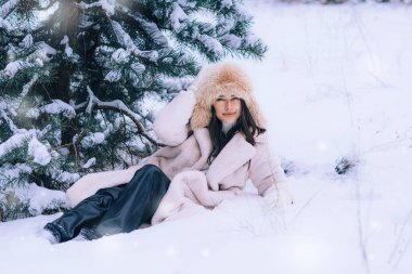 Ormanda donmuş bir karın üzerine uzanmış güzel bir genç kadının portresi. Kürk şapkalı ve ceketli bir kadın. Kış moda koleksiyonu