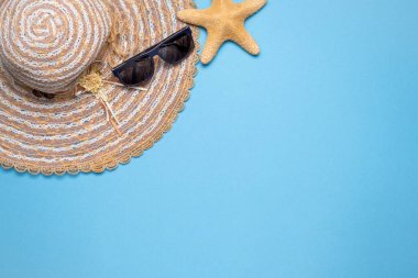 Yaz ve tatil dairesi, hasır şapka, güneş gözlüğü ve mavi arka planda yıldız balığıyla yatıyordu..