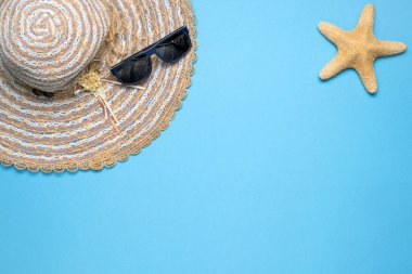 Yaz ve tatil dairesi, hasır şapka, güneş gözlüğü ve mavi arka planda yıldız balığıyla yatıyordu..
