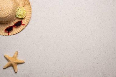 Yaz, sahil ve bedava mesaj alanı olan tatil konsepti. Üst Manzara. Kadın hasır şapkası, güneş gözlüğü ve sol üst köşede kumlu arka planda bir deniz yıldızı olan düz bir düzen.