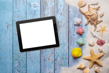 Yaz, sahil ve bedava mesaj alanı olan tatil konsepti. Üst Manzara. Küçük bir grup renkli lastik ördek ve boş bir tablet, büyük deniz yıldızı ve deniz kabuğu ve çeşitli deniz kabukları ve eski mavi tahta sırtında ince kumsal kumu olan düz bir düzen.