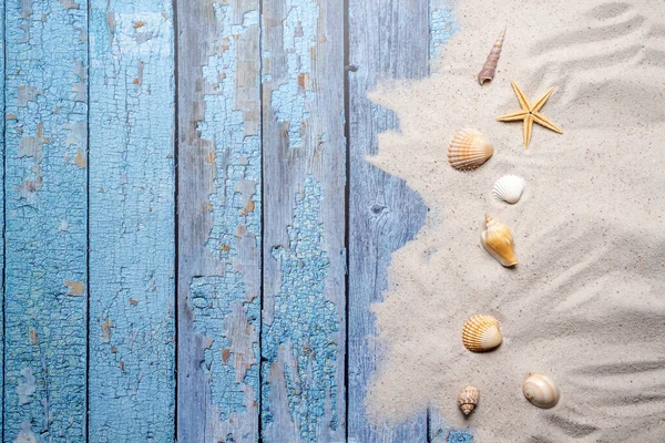 海滩和度假的概念与免费的文字空间 顶部视图 蓝色旧木板背景上有各种海贝壳和细沙的扁平布局 — 图库照片