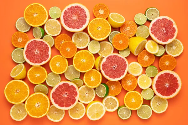 果香和多汁水果的概念 顶部视图 鲜切片和半切柑橘类水果几乎完全覆盖橙色背景 — 图库照片