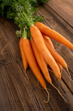 Haftalık market konseptinden taze sebzeler - sağlıklı yaşam ve alışveriş. Haftalık pazardan bir demet taze havuç, ahşap arka planda..