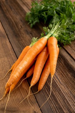 Haftalık market konseptinden taze sebzeler - sağlıklı yaşam ve alışveriş. Haftalık pazardan bir demet taze havuç, ahşap arka planda..