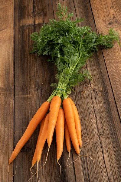 Fresh vegetables from the weekly market concept - healthy living and shopping. Bunch of fresh carrots from the weekly market on a rustic wooden background.