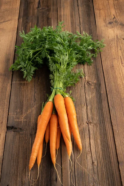 Fresh vegetables from the weekly market concept - healthy living and shopping. Bunch of fresh carrots from the weekly market on a rustic wooden background.