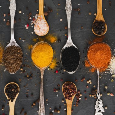 Bir sürü değişik egzotik baharat yemek kaşıkları üzerinde metal ve küçük tahta kaşıklar kare şeklinde dizilmiş büyük bir levha ve ek biber mısır.