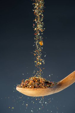 Aromatik baharat karışımı yukarıdan ahşap bir kaşığa düşer. Gurme yemek pişirme ve lezzet geliştirme temaları için harikadır..