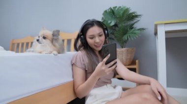 Tatil konsepti 4k Çözünürlük. Asyalı kadın yatak odasında oturmuş müzik dinliyor..