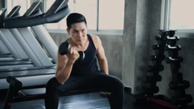 Fitness konsepti 4k Çözünürlük. Genç Asyalı erkekler spor salonunda dambılları kaldırıyor..