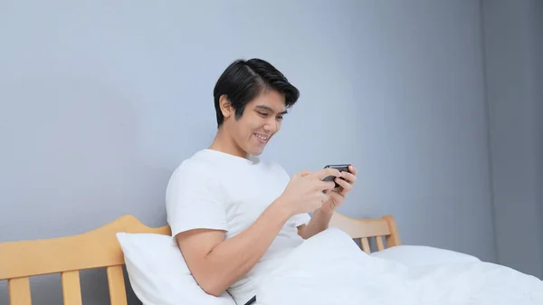 Праздничная Концепция Resolution Азиатский Мужчина Играет Мобильную Игру Спальне Онлайн — стоковое фото