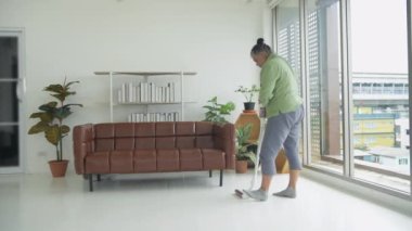 Tatil konsepti 4k Çözünürlük. Asyalı yaşlı bir kadın oturma odasını süpürüyor..