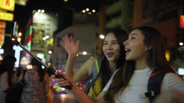 Travel concept of 4k Resolution. A beautiful girl is taking pictures on the pedestrian street at night.