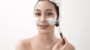 Spa konsepti 4k Çözünürlük. Asyalı kadın yatak odasında yüz kremi sürüyor. Çamur maskeli. yeşil çay özü.