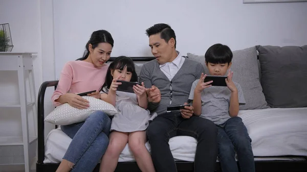 Family concept of 4k Resolution. Asian parents and children playing with mobile phones in the living room