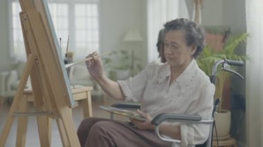 Sanatçı konsepti 4k Çözünürlük. Asyalı kadın oturma odasında resim çiziyor. Sanatçı iş yaratıyor. Engelli insanlar hobi yaratıyor..