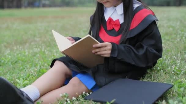 Educational Concept Resolution Asian Girl Graduation Gown Reading Book Garden — Stock Video