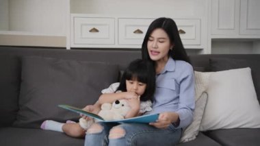 Family concept of 4k Resolution. Mother and daughter are reading books together in the living room.