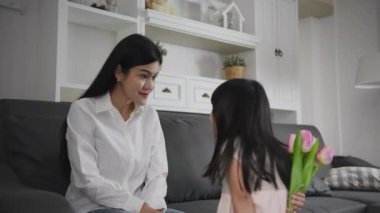 Family concept of 4k Resolution. Asian daughter giving flowers to mother in living room.