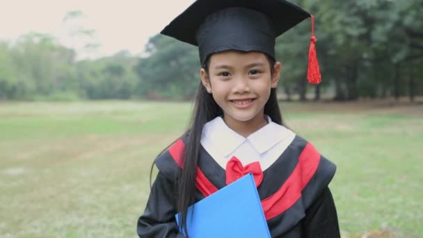 4K分辨率的教育概念 身着毕业礼服的亚洲女孩带着对花园的信心微笑 — 图库视频影像