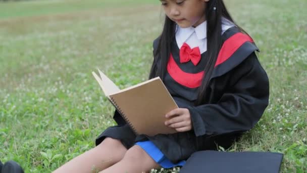 Educational Concept Resolution Asian Girl Graduation Gown Reading Book Garden — Stock Video