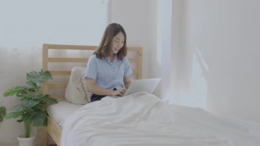 Tatil konsepti 4k Çözünürlük. Yatak odasında bilgisayarla çalışan Asyalı kızlar..