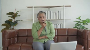 Tatil konsepti 4k Çözünürlük. Asyalı yaşlı kadın evde şarkı söyleyerek eğleniyor..