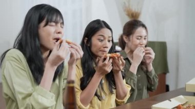 Tatil konsepti 4k Çözünürlük. Bir grup Asyalı bayan arkadaş evde birlikte pizza yiyorlar. Eğlenceli ve heyecan verici eğlence aktiviteleri.