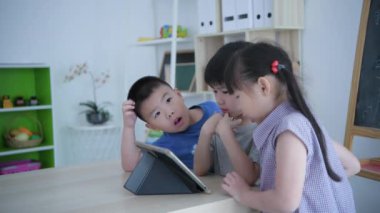 Eğitici 4k çözünürlük kavramı. Anaokulu öğretmeni sınıfta tablet kullanarak çocuklara öğretiyor..
