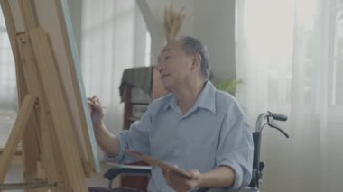 Sanatçı konsepti 4k Çözünürlük. Asyalı adam oturma odasında resim yapıyor. Sanatçı iş yaratıyor. Boş zaman aktiviteleri ve hobileri.